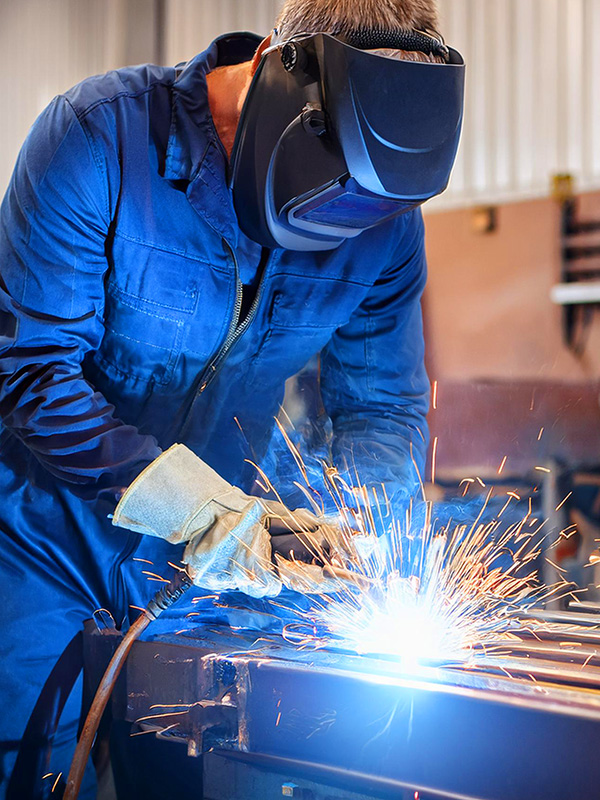 welder carrying out general steel fabrication blue overalls